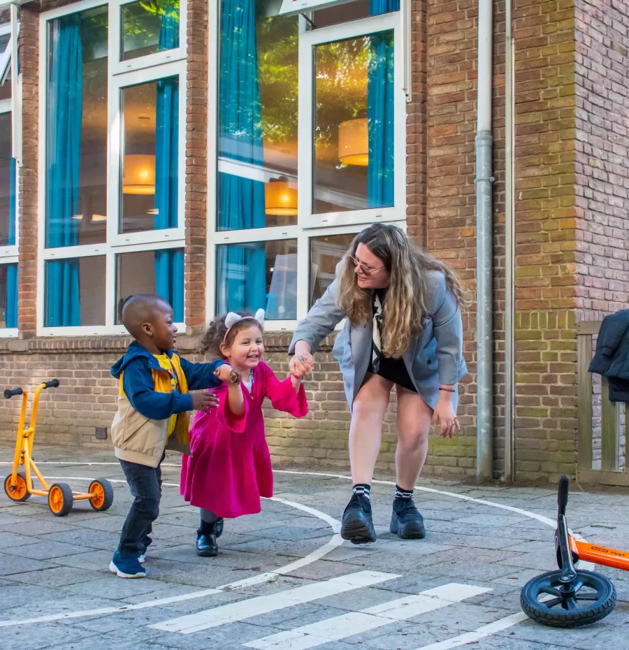 Peuterspeelzaal Wilhelmini pedadogisch medewerkster met kindjes buiten spelen