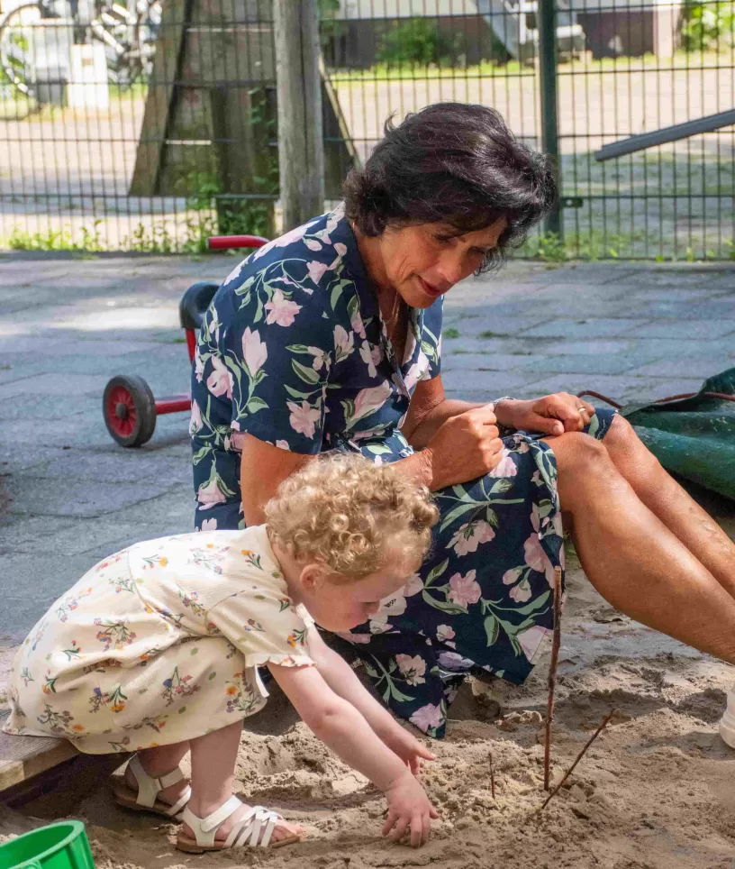 Pedagogisch medewerker met meisje in de zandbak